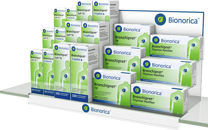 Mehrstufiges Acryl-Regaldisplay gefüllt mit grünen Bronchipret-Medikamentenpackungen von Bionorica.