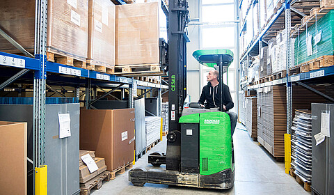 Person im Logistiklager in einem Gabelstabler