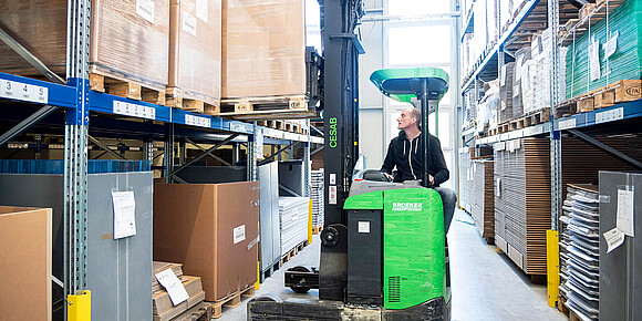 Person im Logistiklager in einem Gabelstabler