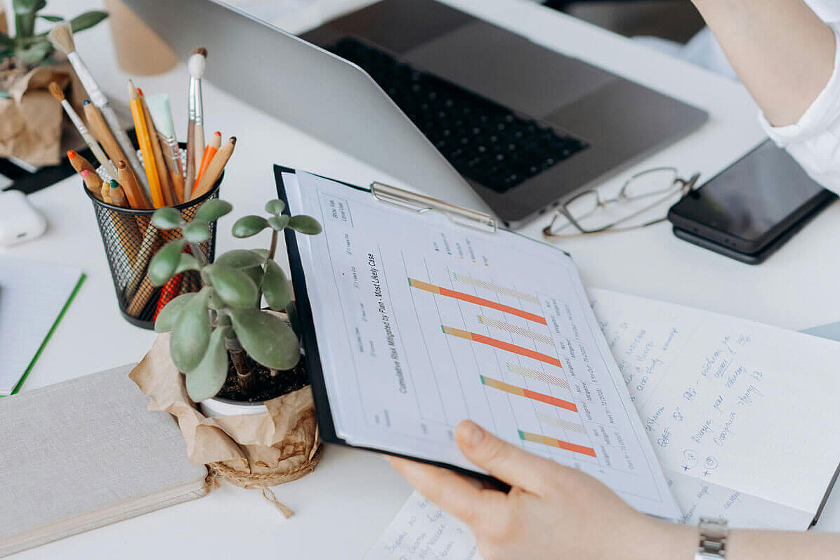 Zwei Personen am Tisch mit LapTop und Grafiken und Statistiken