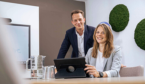 Zwei Mitarbeiter im Konferenzraum am Tisch vor einem LapTop