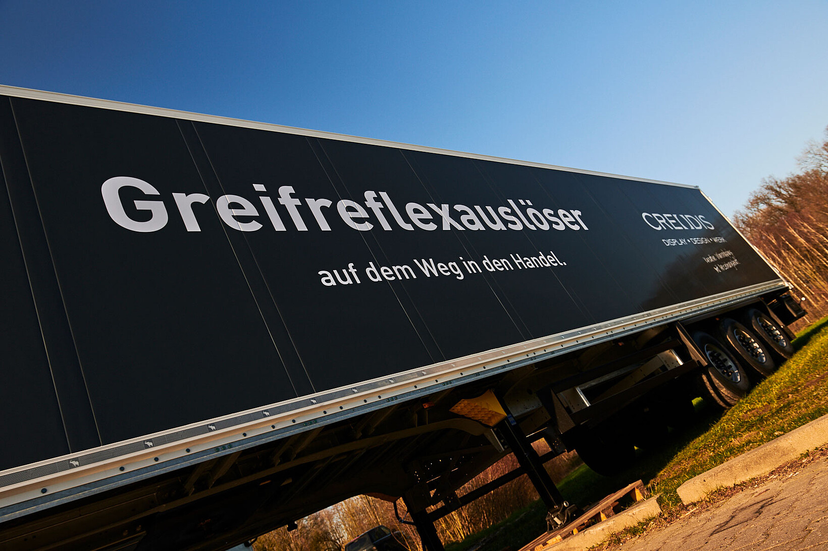 Schwarzer LKW-Trailer mit großem weißen Text Greifreflexauslöser auf dem Weg in den Handel.