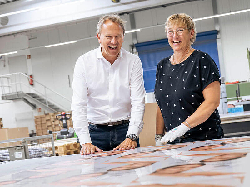 Zwei Personen stehen in der Produktion vor einem Tisch mit Mustern